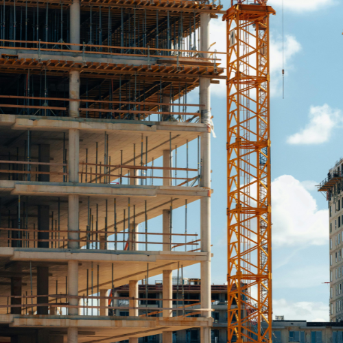 Construction site with building skeleton and crane assembling steel framework.
